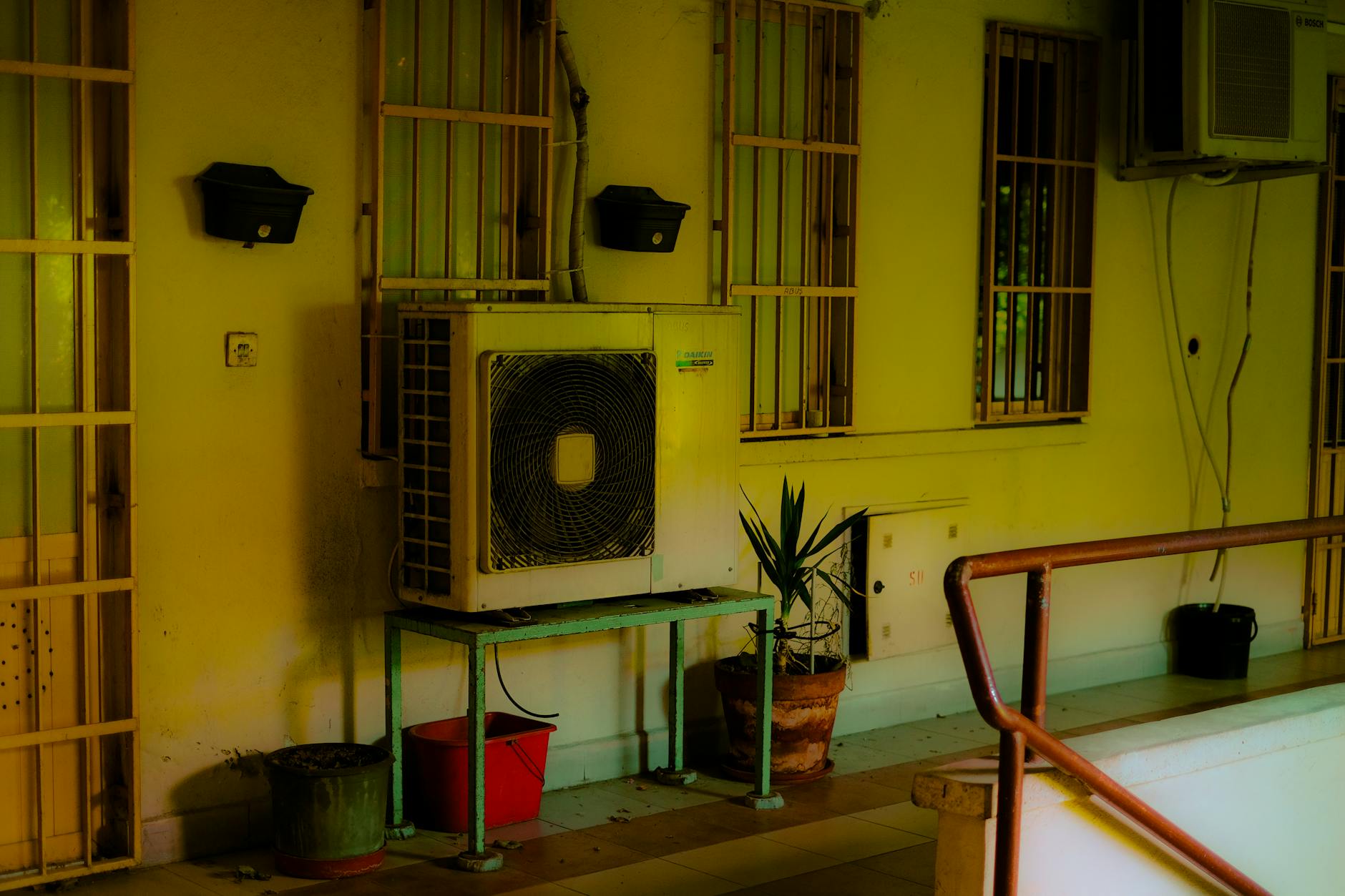 Jednostka klimatyzacji na balkonie z roślinami w miejskiej zabudowie