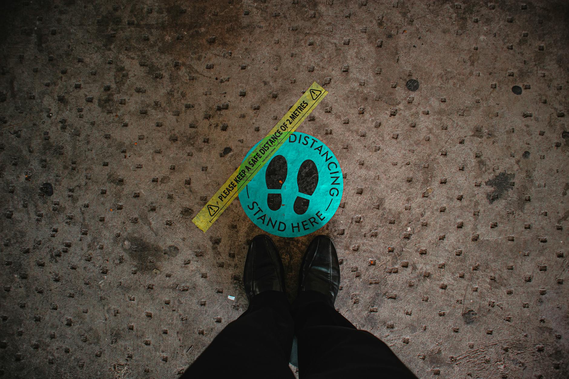 Mężczyzna w eleganckich butach stoi na znaku dystansu społecznego