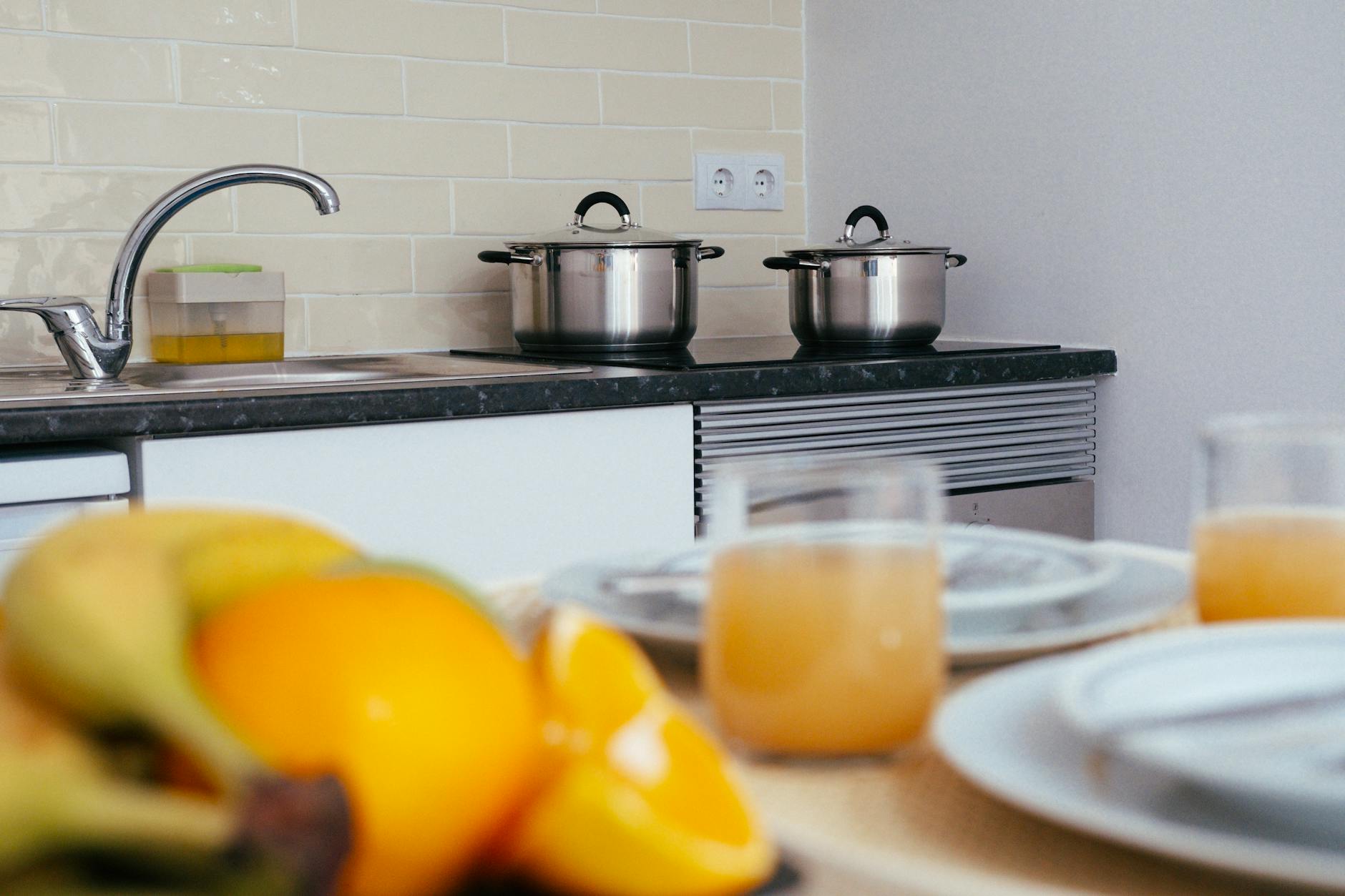 Nowoczesna kuchnia z drewnianym stołem, owocami i sokiem pomarańczowym