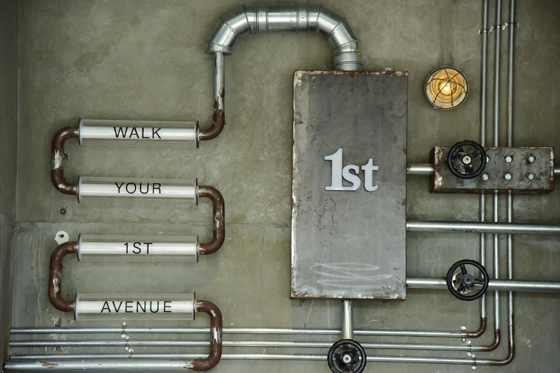 Betonowa ściana z industrialnymi rurami i vintage’owym napisem