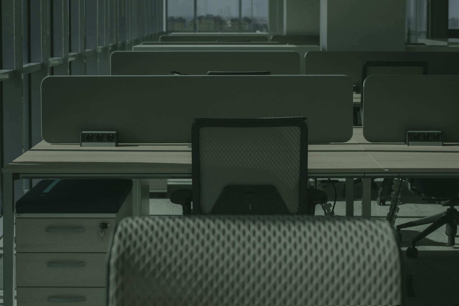 Nowoczesne biuro z kilkoma pustymi biurkami i ergonomicznymi krzesłami