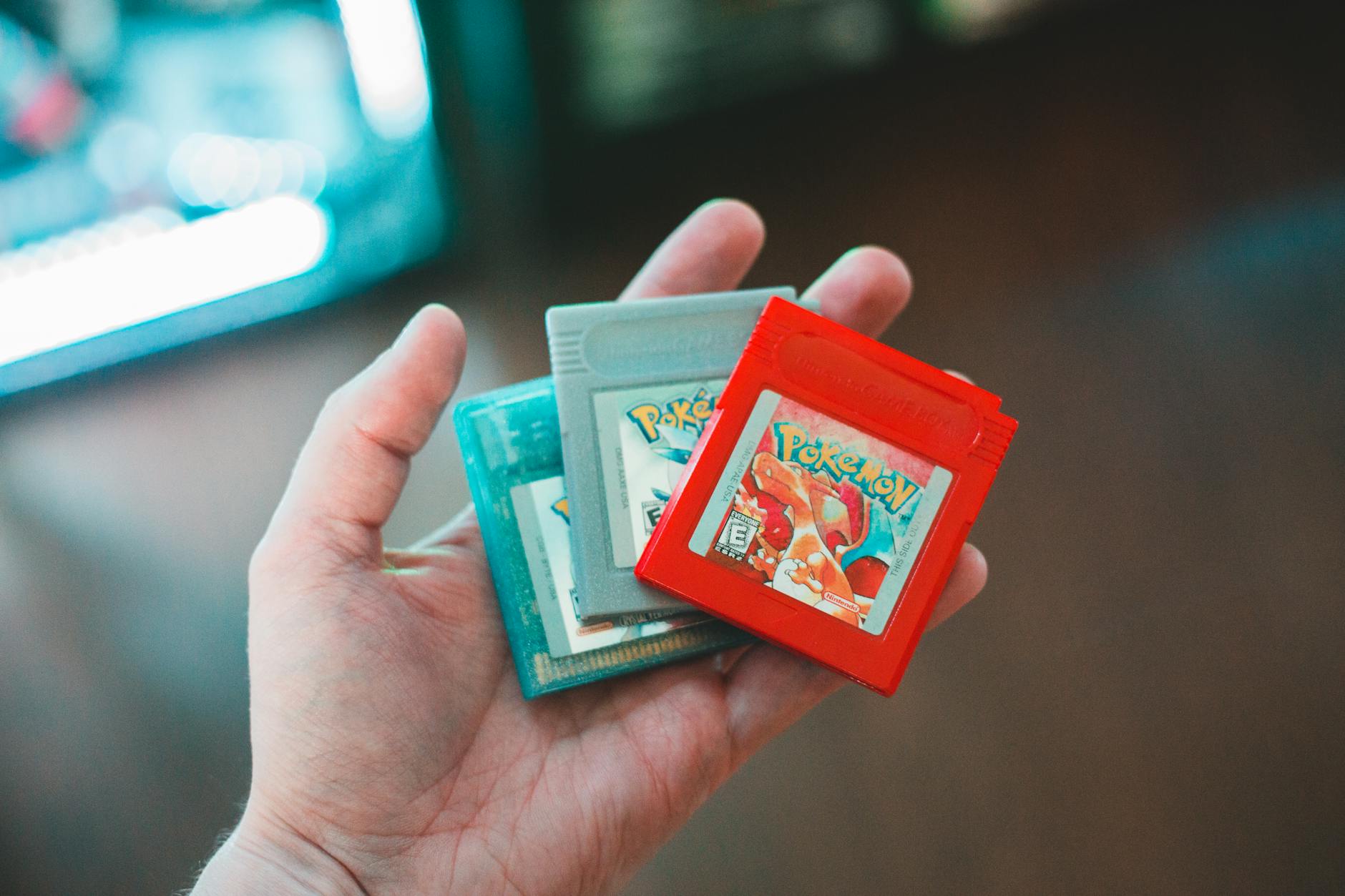 Dłoń trzymająca stare kartridże gier Pokemon, symbol nostalgii gracza
