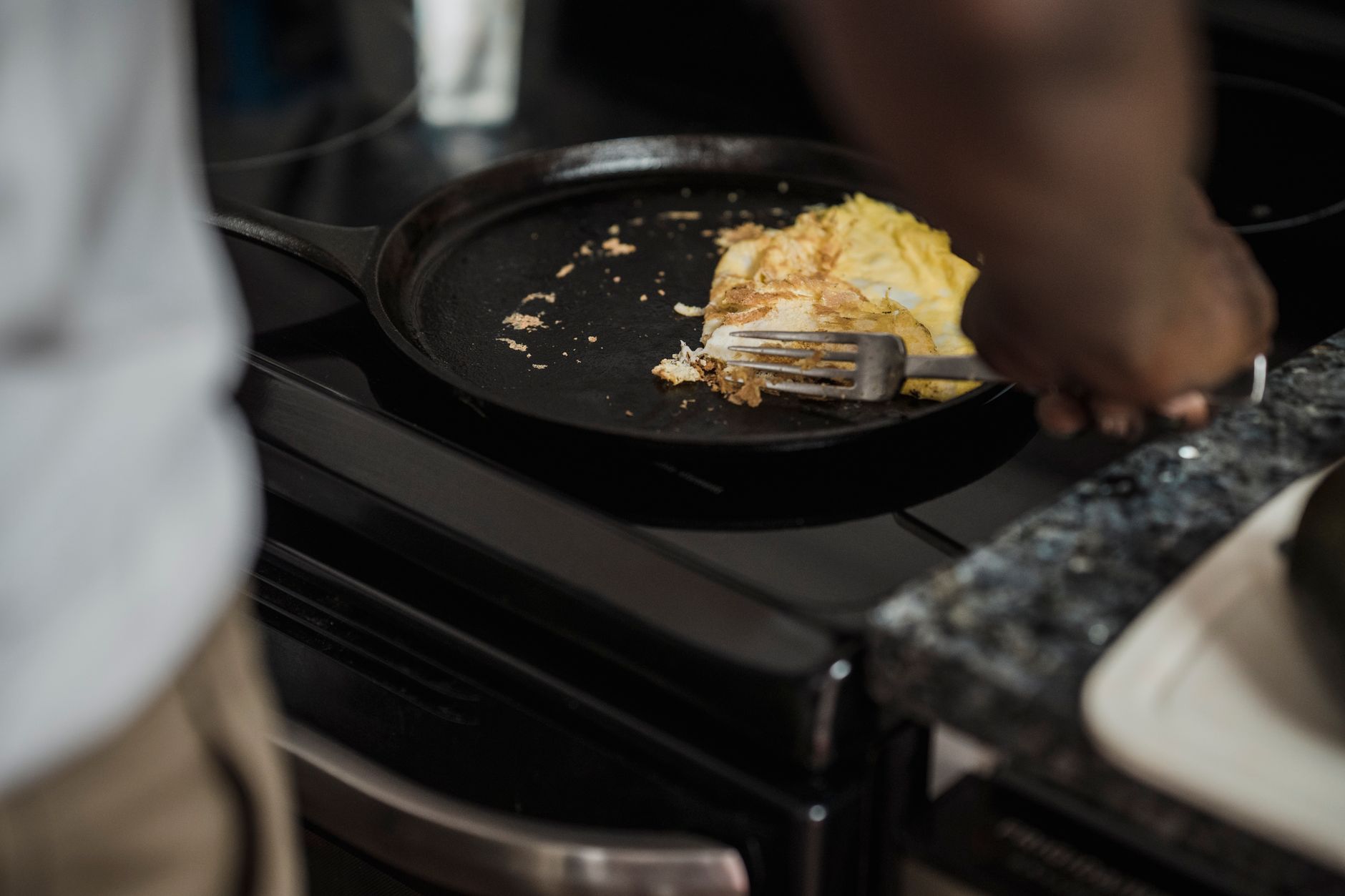 Mężczyzna smaży omlet na kuchence gazowej w domowej kuchni