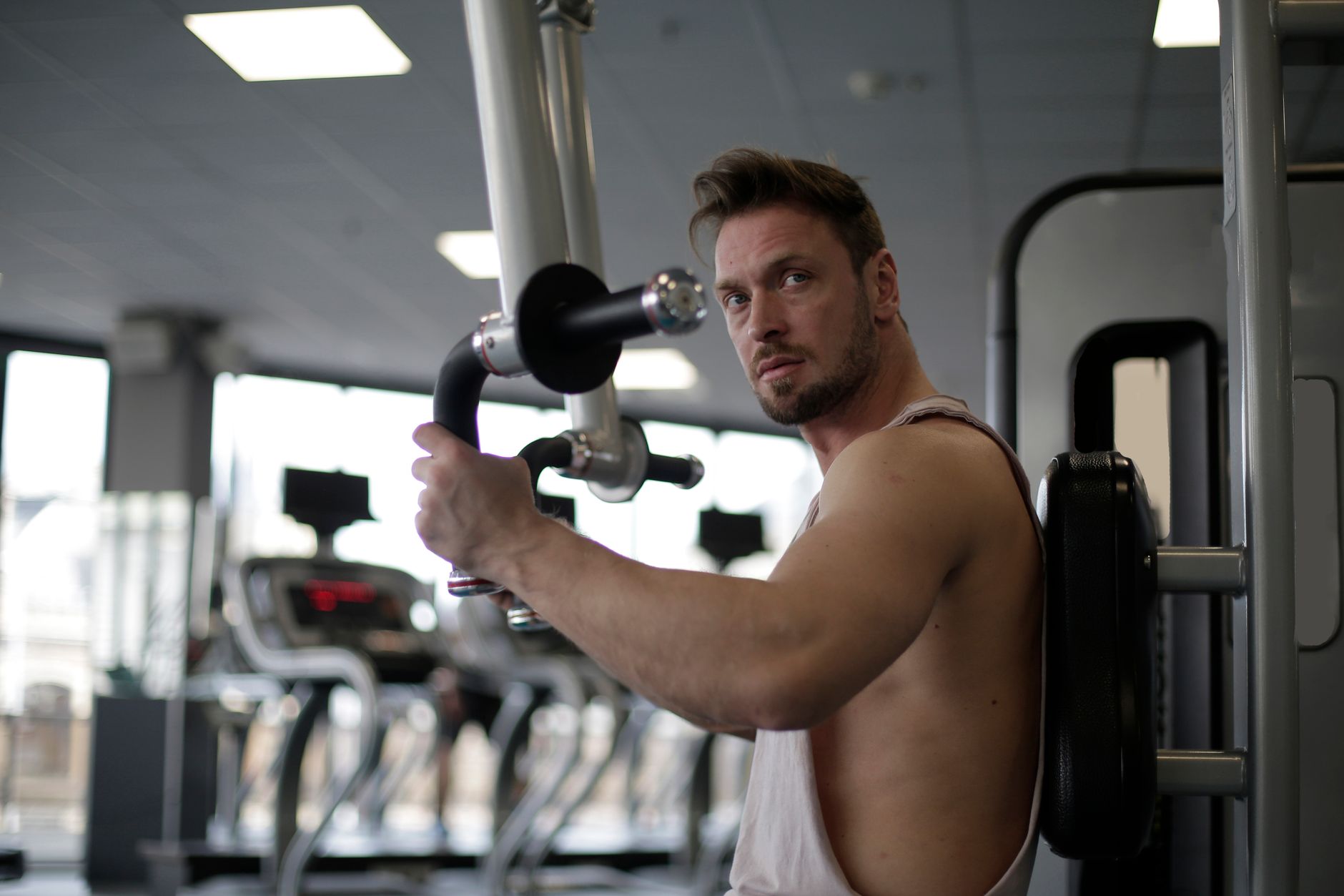 Skupiony mężczyzna ćwiczący biceps na siłowni po przerwie treningowej